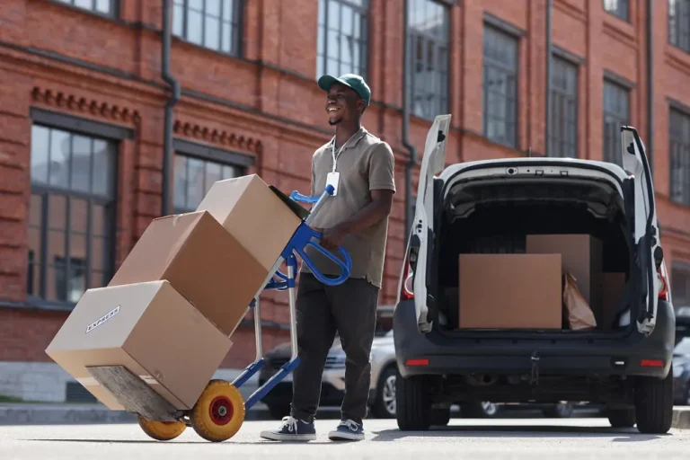 Courier moving boxes on a hand truck from a delivery van