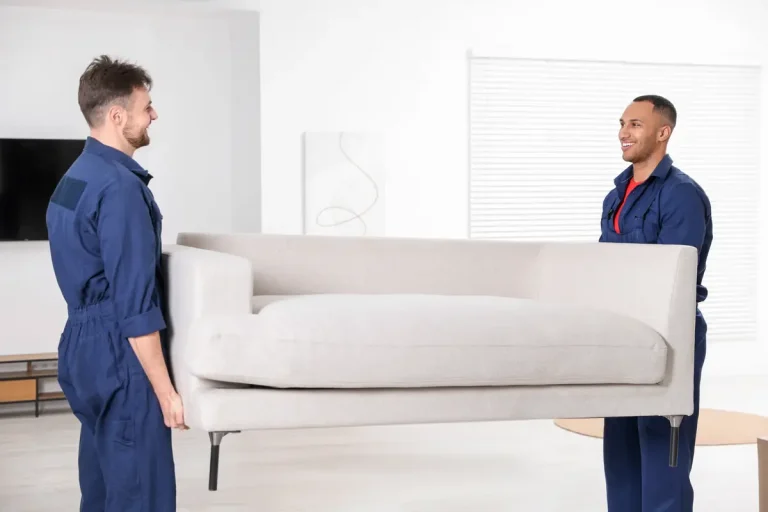 Two movers carrying a sofa through a home
